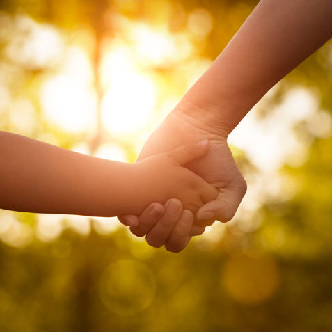 Close up of mother or older sister and a child hands at the sunset